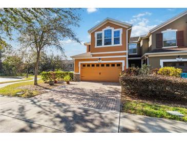 Attractive two-story townhome with a brick driveway and well-manicured landscaping at 9496 Strongbark Ln, Orlando, FL 32832