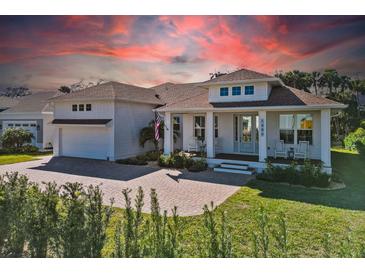 White two-story house with a brown roof, front porch, and a landscaped yard at 1406 Saxon Dr, New Smyrna Beach, FL 32169