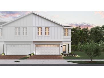 Two-story townhome with white siding, two-car garage, and landscaping at 205 Glass Onion Dr, Howey In The Hills, FL 34737