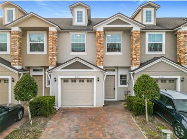 Tan two-story townhome with stone accents and a two-car garage at 3196 Crown Jewel Ct, Winter Park, FL 32792