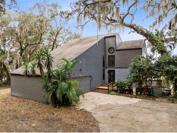 Gray two-story house with attached garage and landscaping, situated on a tree-lined property at 41235 Silver Dr, Umatilla, FL 32784