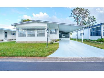 White single-wide mobile home with carport and landscaped lawn at 1401 W Highway 50 # 68, Clermont, FL 34711