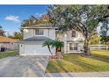 Two-story house with white exterior, a white garage door, and a palm tree in the front yard at 1727 Wood Violet Dr, Orlando, FL 32824