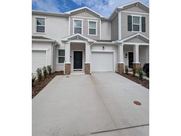 Exterior of a two-story townhome with a two-car garage and landscaping at 2499 Skyline Loop, Kissimmee, FL 34758