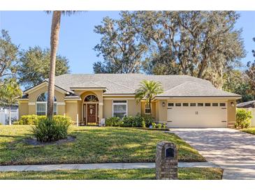 Tan one-story house with gray roof, two-car garage, and manicured lawn at 960 Manchester Ave, Oviedo, FL 32765