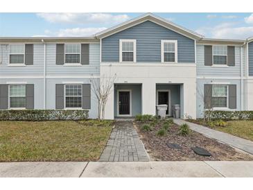 Two-story townhome with gray siding, shutters, and a brick walkway at 297 Jetty Way, Davenport, FL 33897