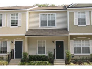 Tan townhome with dark gray door, shutters, and landscaping at 4145 Plantation Cove Dr, Orlando, FL 32810