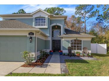 Two-story house with a green exterior, two-car garage, and landscaped front yard at 611 Buckhaven Loop, Ocoee, FL 34761