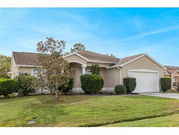 Tan house with a white garage door and well-manicured lawn at 63 York Ct, Kissimmee, FL 34758