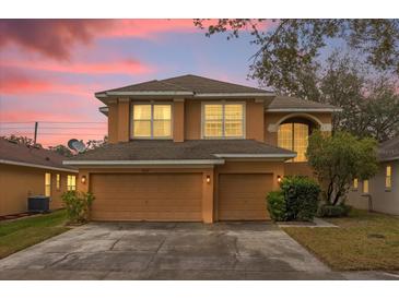 Two-story house with beige exterior, two-car garage, and landscaped yard at 8567 Baywood Vista Dr, Orlando, FL 32810