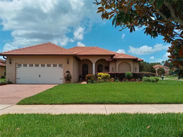 Charming single-story home featuring a red tile roof, lush landscaping, and a well-manicured lawn on a sunny day at 10215 Yonaomi Cir, Clermont, FL 34711