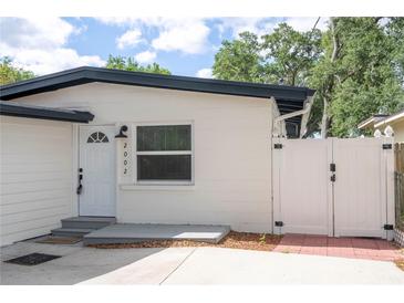 Charming home featuring a white exterior, dark roof, and well-maintained landscaping and gated entry at 2002 Geigel Ave, Orlando, FL 32806