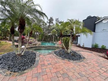 Inviting pool area with a spa, waterfall feature, and brick patio at 4010 Winderlakes Dr, Orlando, FL 32835