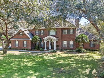 Charming two-story red brick home with a well-manicured lawn and mature trees at 9501 Hempel Cove Blvd, Windermere, FL 34786