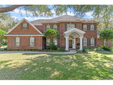 Traditional brick home featuring mature landscaping and a welcoming entrance with white columns at 9501 Hempel Cove Blvd, Windermere, FL 34786