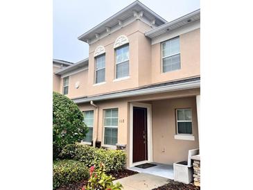 Tan two-story townhome with a brown door and landscaping at 112 Augustus Pt, Sanford, FL 32773