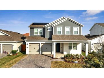 Two-story house featuring gray siding, solar panels, and a two-car garage at 14789 Milfoil Ave, Orlando, FL 32827