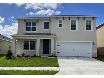 Two-story house with a neutral color scheme, a two-car garage, and a well-maintained lawn at 2912 Moulin Rd, Davenport, FL 33837