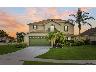 Two-story house with green garage door and landscaped lawn at 3235 Abiaka Dr, Kissimmee, FL 34743