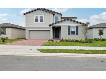 Charming two-story home featuring a gray exterior, brick driveway, and well-manicured landscaping at 3833 Giorgio Dr, Winter Haven, FL 33884