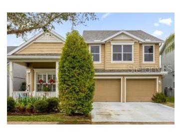 Two-story house with beige siding, three-car garage, and covered porch at 4220 Cleary Way, Orlando, FL 32828