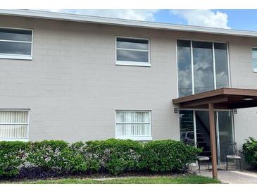 A traditional condominium exterior with large windows, trimmed hedges, and a covered entrance with chairs at 5885 Dahlia Dr # 29/115, Orlando, FL 32807