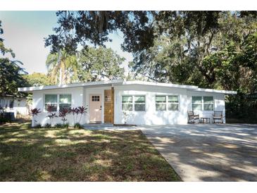 Updated mid-century modern home with a pink door and manicured lawn at 7007 Seminole Dr, Belle Isle, FL 32812