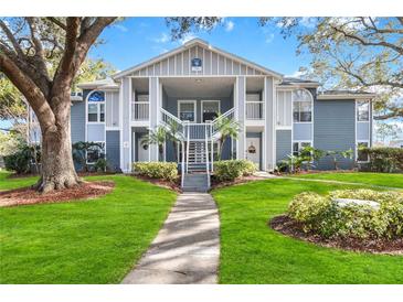 Two-story building with light blue exterior, lush landscaping, and ample parking at 731 Sugar Bay Way # 103, Lake Mary, FL 32746