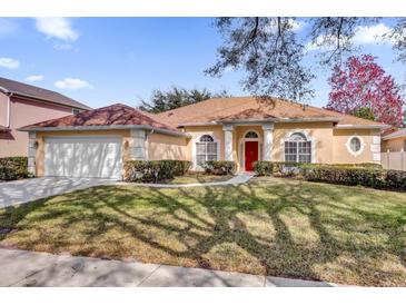 One-story house with a brown roof, attached garage, and well-manicured lawn at 7895 Saint Giles Pl, Orlando, FL 32835