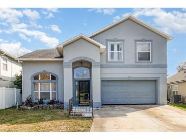 Charming two-story home with blue gray facade, arched windows, and an attached two-car garage at 7909 Chartreux Ln, Maitland, FL 32751