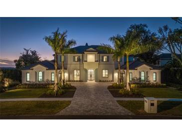 Elegant two-story home with a stunning facade and landscaping at night at 9122 Bay Point Dr, Orlando, FL 32819