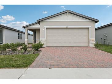 Charming single Gathering home featuring a two-car garage and landscaped front yard with a brick paver driveway at 1373 Current Pl, Haines City, FL 33844