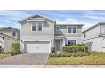 Two-story house with gray siding, a two-car garage, and a landscaped front yard at 17584 Saw Palmetto Ave, Clermont, FL 34714