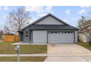 Newly renovated home with gray siding, two-car garage, and landscaped lawn at 2201 Kentucky Derby Dr, Orlando, FL 32825