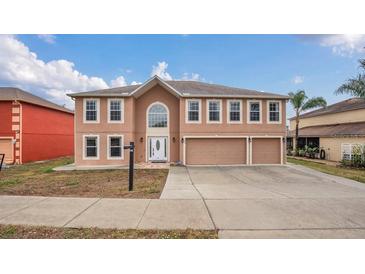 Two-story house with a three-car garage and tan exterior at 3433 Glossy Leaf Ln, Clermont, FL 34711