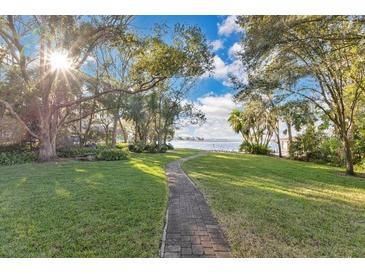 Brick pathway meanders through lush green lawn towards scenic waterfront at 4108 Downeast Ln, Windermere, FL 34786