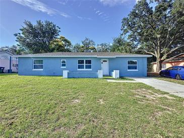 Newly renovated light blue house with a well-maintained lawn and driveway at 7211 Pinion Dr, Orlando, FL 32818