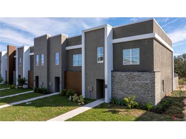 Modern townhome with gray exterior, stone accents, and walkway at 9029 Ibiza Ln # 1, Kissimmee, FL 34747