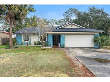 Cute light blue house with a white garage door and well-maintained lawn at 905 Suwannee Dr, Apopka, FL 32703