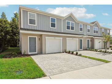 Three-unit townhome building with gray siding, white garage doors, and paved driveways at 1102 Fan Palm Dr, Davenport, FL 33897