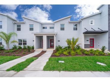 Modern townhome with gray exterior, red doors, and landscaping at 2992 Protagonist St, Kissimmee, FL 34746