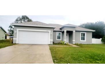 Gray house with a white garage door and a well-maintained lawn at 615 N Delmonte Ct, Kissimmee, FL 34758