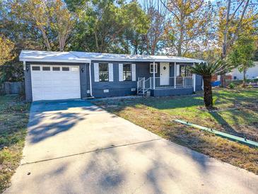 Gray house with white garage door and landscaped yard at 6952 Sw 85Th Pl, Ocala, FL 34476