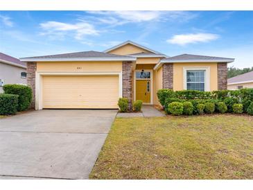 One-story house with a yellow exterior, a two-car garage, and well-manicured landscaping at 841 Greenshank Dr, Haines City, FL 33844