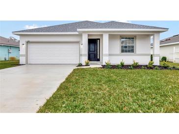 New construction home with white exterior, two-car garage, and landscaped lawn at 925 Magnolia Ave, Holly Hill, FL 32117