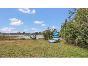 Kayaks and a dock sit on the grassy lakeside backyard at 1296 W Wellington Dr, Deltona, FL 32725