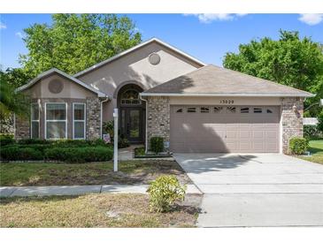 One-story house with brick and neutral siding, attached two-car garage, and landscaping at 13029 Cog Hill Way, Orlando, FL 32828