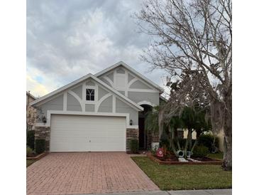 Two-story house with a gray exterior, brick driveway, and landscaped yard at 16036 River Pointe Ct, Orlando, FL 32828