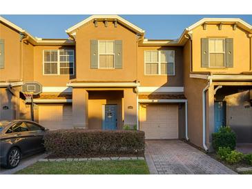 Tan two-story townhome with two-car garage, basketball hoop, and landscaped front yard at 16583 Cedar Crest Dr, Orlando, FL 32828