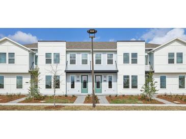 Three-unit townhome building with modern design, landscaping, and a light color scheme at 6581 Quest St, St Cloud, FL 34771